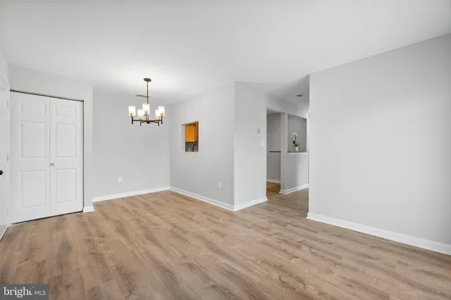an empty room with wooden floor and kitchen view