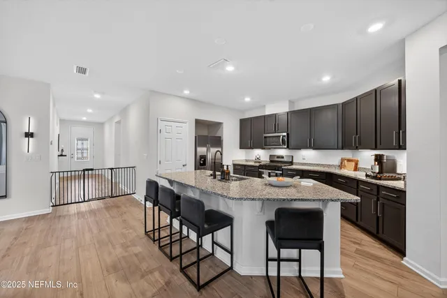 a kitchen with stainless steel appliances granite countertop a table chairs sink refrigerator and cabinets