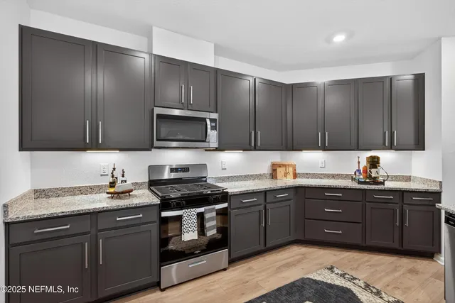a kitchen with stainless steel appliances granite countertop a sink stove and microwave