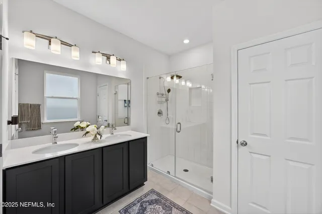 a bathroom with a double vanity sink mirror and shower