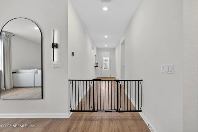 a view of a hallway with wooden floor and bathroom