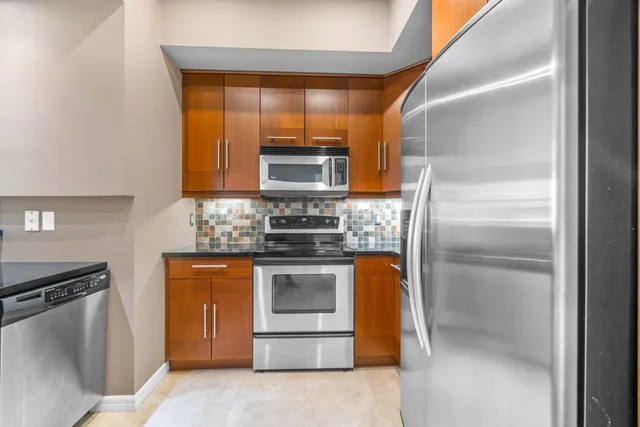 a kitchen with stainless steel appliances granite countertop a refrigerator and a stove top oven
