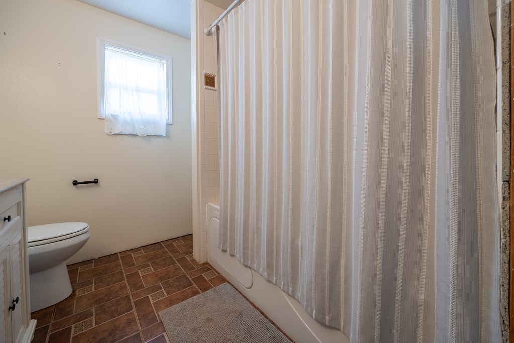 1596 Mule Creek Road Robert Lee, TX 76945 - Photo 13 of 98 a bathroom with a toilet and a shower curtain