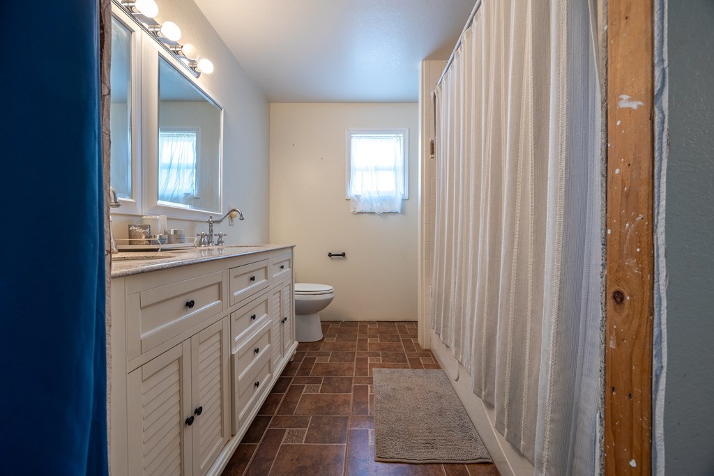 1596 Mule Creek Road Robert Lee, TX 76945 - Photo 29 of 98 a spacious bathroom with a double vanity sink a toilet and a mirror
