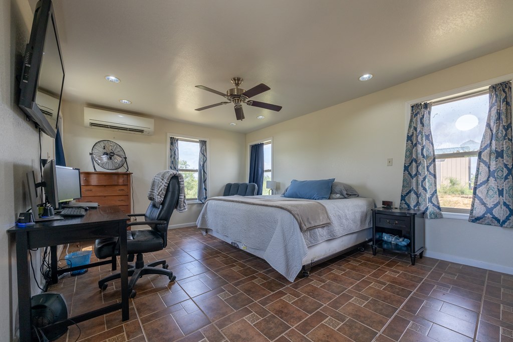 1596 Mule Creek Road Robert Lee, TX 76945 - Photo 3 of 98 a bedroom with a bed a desk and chair with wooden floor