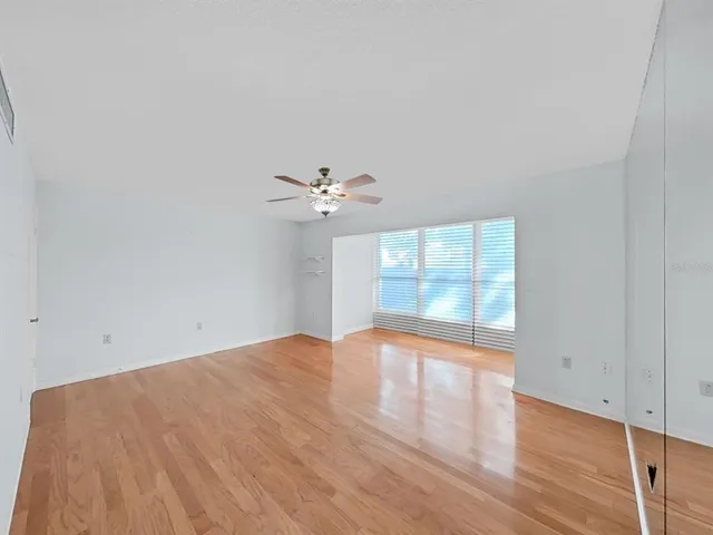 a view of empty room with wooden floor and fan
