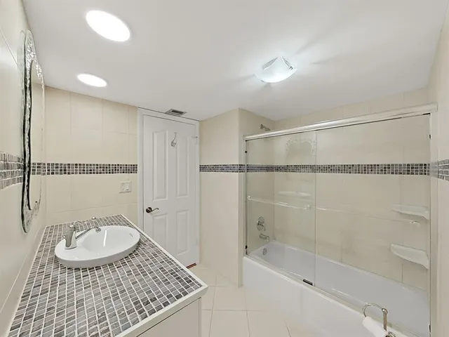 a bathroom with a granite countertop sink a mirror and shower