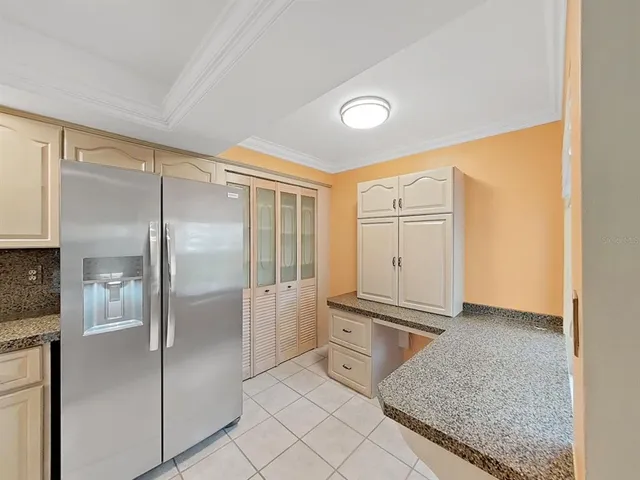 a kitchen with granite countertop a refrigerator and cabinets
