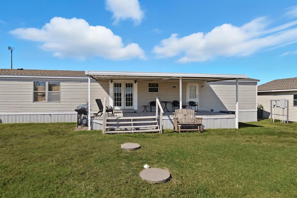 Back of property featuring a yard, a wooden deck, and french doors