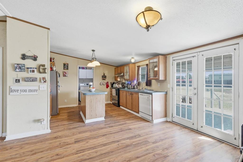 1200 Alliance Boulevard Rhome, TX 76078 - Photo 16 of 31 Kitchen with french doors, light wood-type flooring, ornamental molding, black / electric stove, and white dishwasher