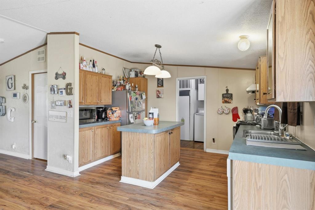 1200 Alliance Boulevard Rhome, TX 76078 - Photo 17 of 31 Kitchen featuring crown molding, light wood-type flooring, vaulted ceiling, a kitchen island, and stainless steel appliances