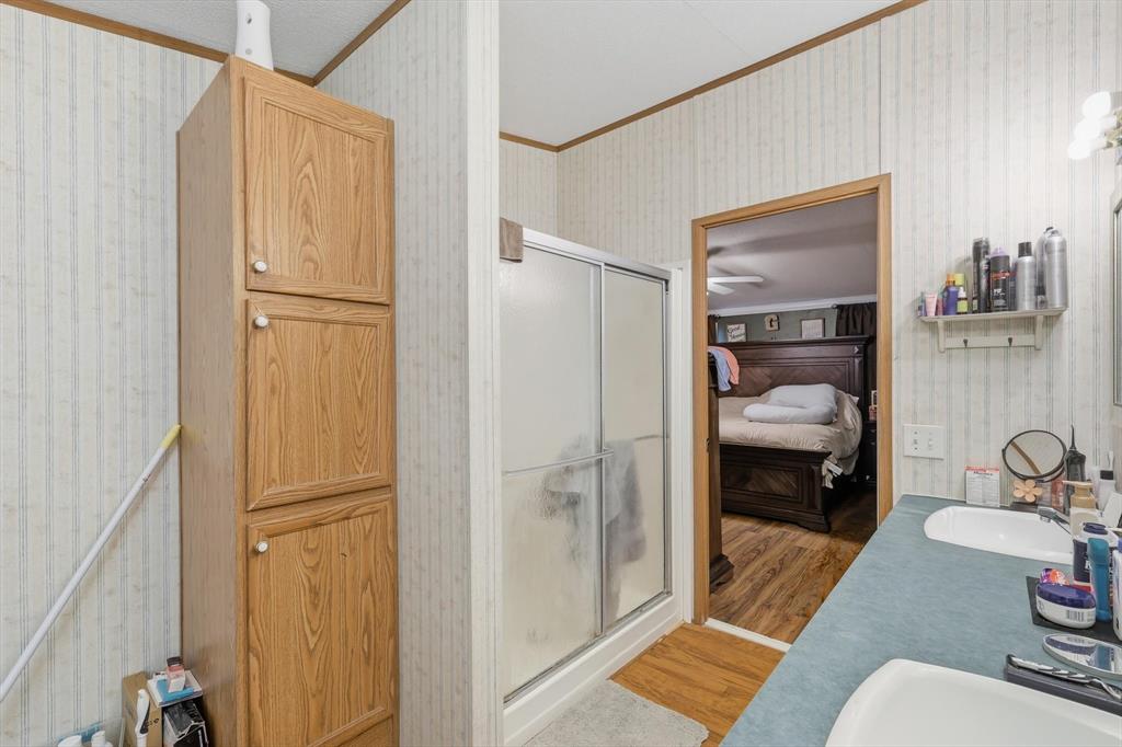 1200 Alliance Boulevard Rhome, TX 76078 - Photo 24 of 31 Ensuite bathroom with wallpapered walls, crown molding, a stall shower, and light wood-style flooring