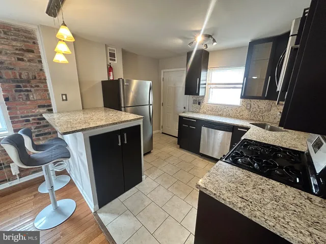 a kitchen with granite countertop a stove a sink and a refrigerator