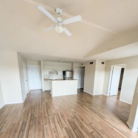 a view of a kitchen with wooden floor and a ceiling fan