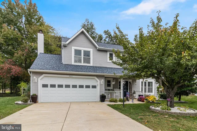 a front view of a house with a garden and trees