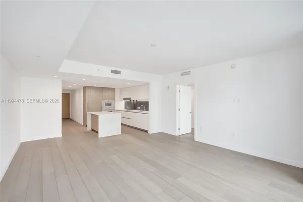 a large white kitchen with a sink and refrigerator
