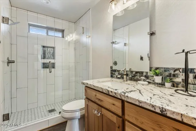 a bathroom with a granite countertop sink a toilet a mirror and shower