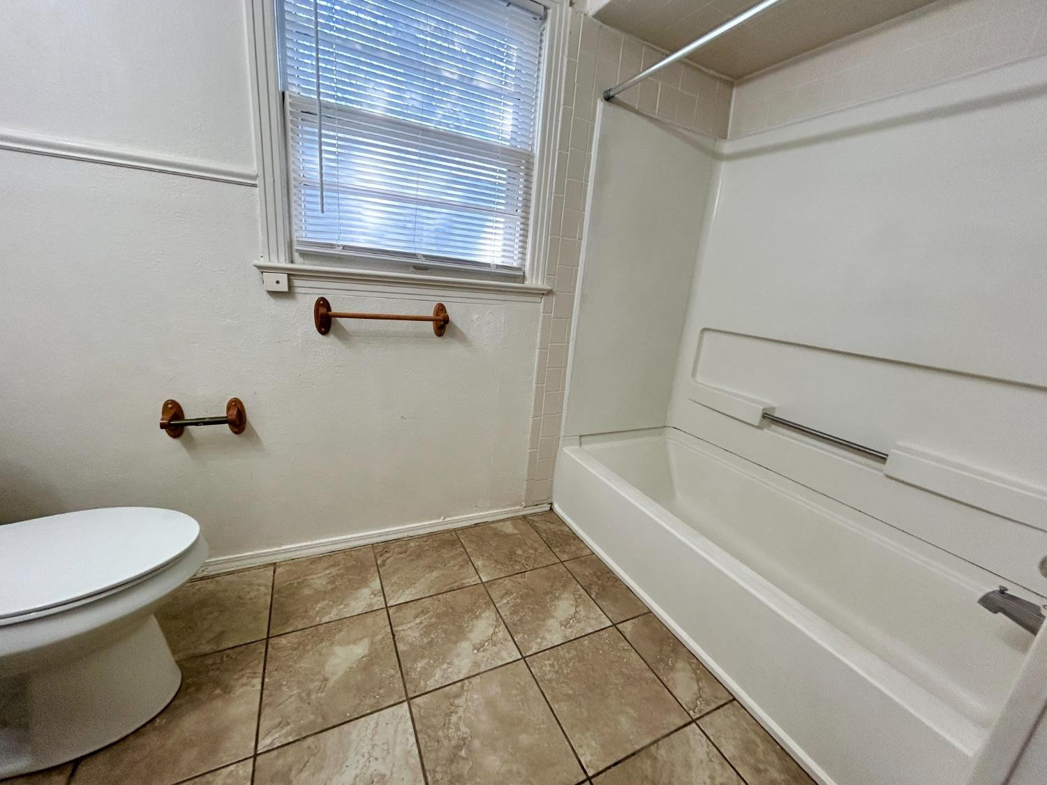 2216 30th Street, Unit FRONT Lubbock, TX 79411 - Photo 4 of 11 a bathroom with a toilet and a bath tub