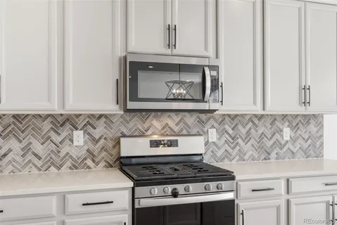 a kitchen with granite countertop white cabinets and a stove