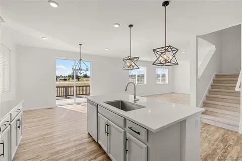 a kitchen with stainless steel appliances granite countertop a sink a island and chairs with wooden floor