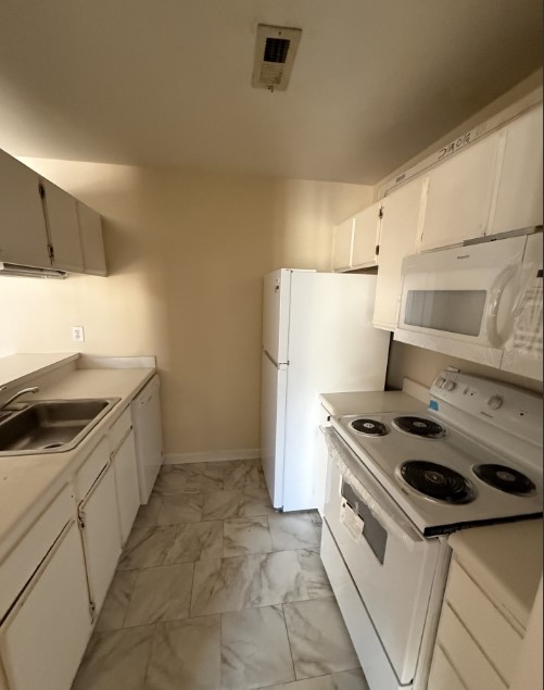 220 Elm Street, Unit 533 Clemson, SC 29631 - Photo 4 of 10 A compact kitchen with white cabinetry and appliances offers practical living.