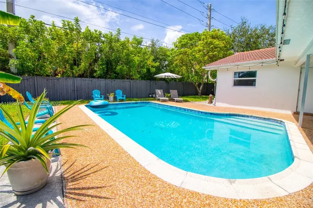 a view of a swimming pool with a yard and wooden fence
