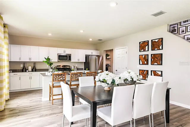 a kitchen with stainless steel appliances kitchen island granite countertop a dining table chairs and white cabinets