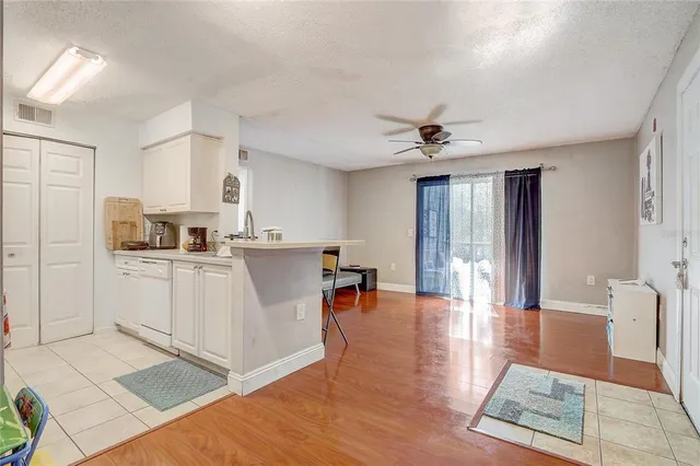 a living room with stainless steel appliances furniture a rug kitchen view and a window