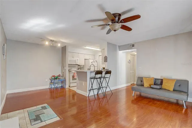 a living room with furniture and kitchen view with wooden floor