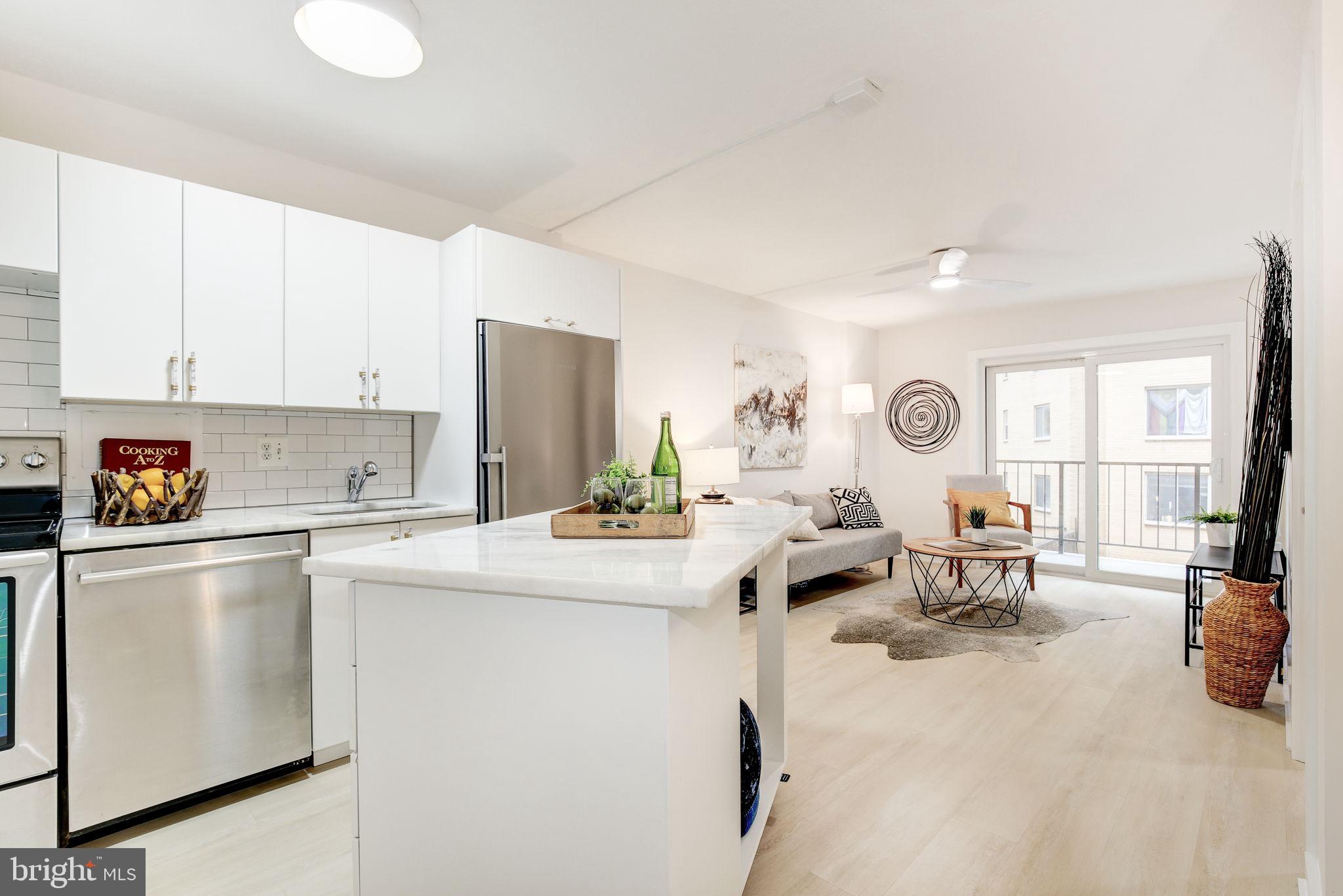 1718 P Street Northwest, Unit 215 Washington, DC 20036 - Photo 1 of 38 a kitchen with stainless steel appliances a stove a sink a refrigerator white cabinets and couches with wooden floor
