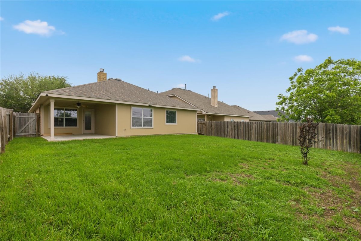17812 Masi Loop Pflugerville, TX 78660 - Photo 34 of 38 Expansive green space featuring a wood fence, mature landscaping, and a covered concrete patio
