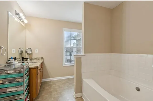 a bathroom with a granite countertop sink a mirror and a bathtub