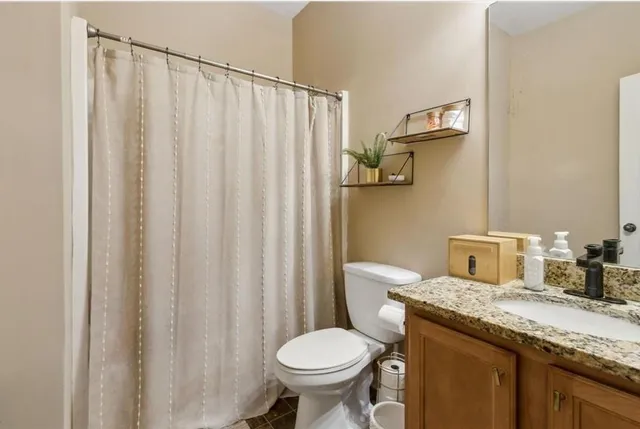 a bathroom with a granite countertop toilet and a sink