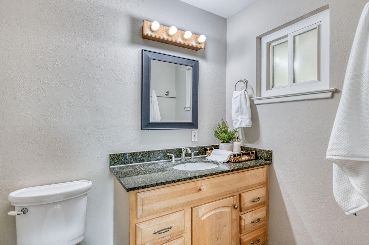638 West Dennis Drive Clovis, CA 93612 - Photo 24 of 33 a bathroom with a granite countertop sink a toilet and mirror