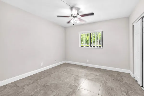 an empty room with windows and fan