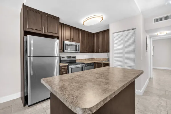a kitchen with stainless steel appliances granite countertop a refrigerator a stove and a sink with wooden floor