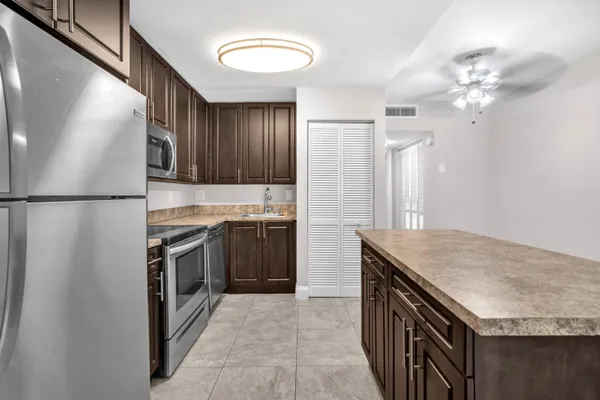 a kitchen with kitchen island granite countertop a sink stove and refrigerator