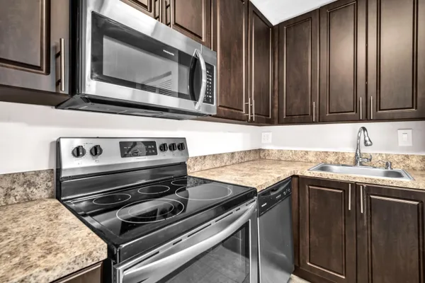 a kitchen with granite countertop a stove microwave and sink