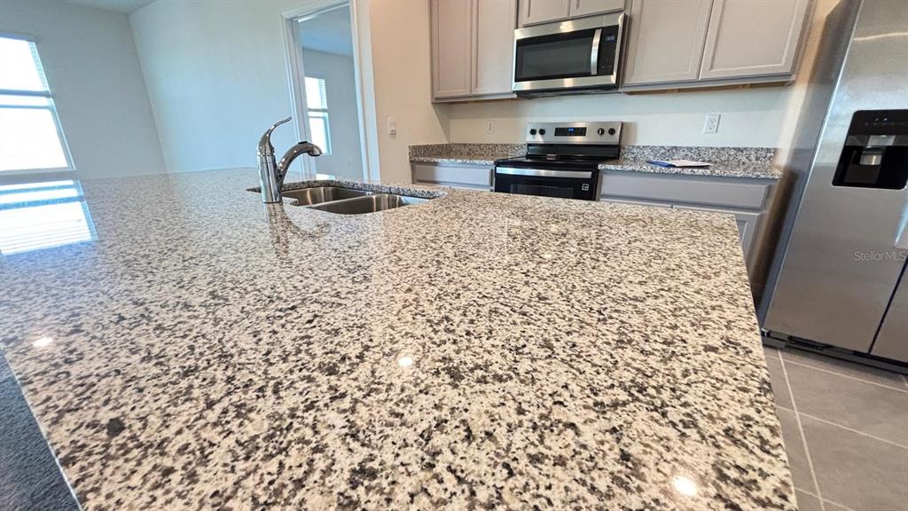 914 Princess Sabal Point Haines City, FL 33844 - Photo 11 of 39 a kitchen with granite countertop a sink and a stove top oven