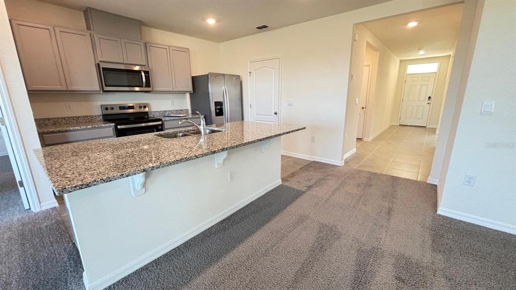 914 Princess Sabal Point Haines City, FL 33844 - Photo 9 of 39 a kitchen with granite countertop a refrigerator and a stove top oven