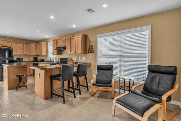 a kitchen with kitchen island granite countertop wooden cabinets a sink dishwasher a stove and a refrigerator with wooden floor
