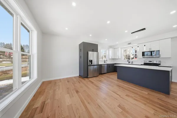 a large kitchen with stainless steel appliances kitchen island a large counter top and a wooden floors