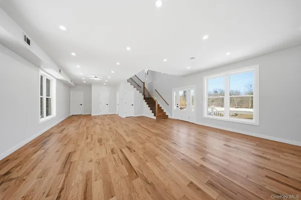 a view of empty room with wooden floor and windows