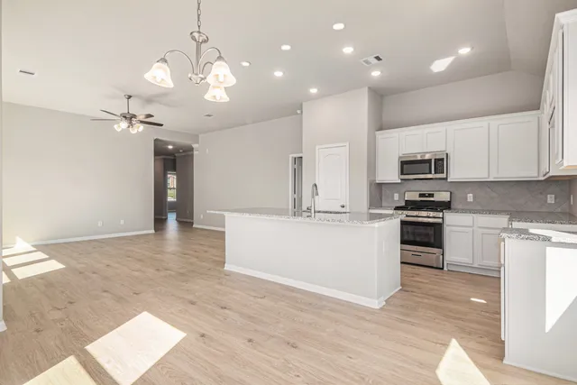 a large kitchen with granite countertop a large counter top a sink stainless steel appliances and cabinets