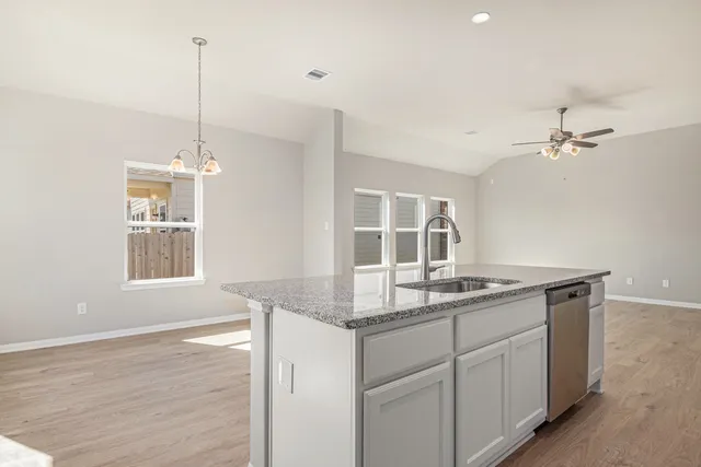 a kitchen with a sink chandelier and living room view