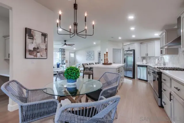 a kitchen with kitchen island a dining table chairs and white cabinets