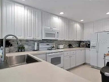 a kitchen with granite countertop white cabinets and white appliances