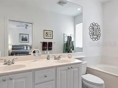 a bathroom with a granite countertop sink toilet and a large mirror