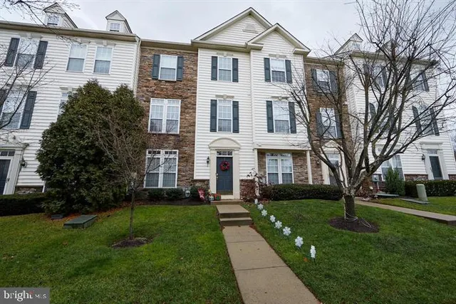 a front view of a house with garden and trees