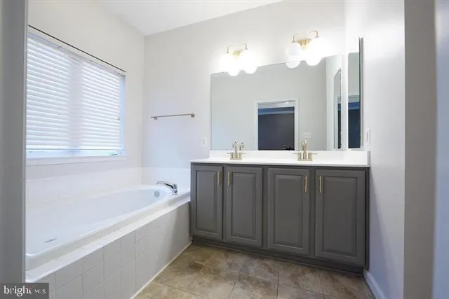a bathroom with a tub a sink and a mirror